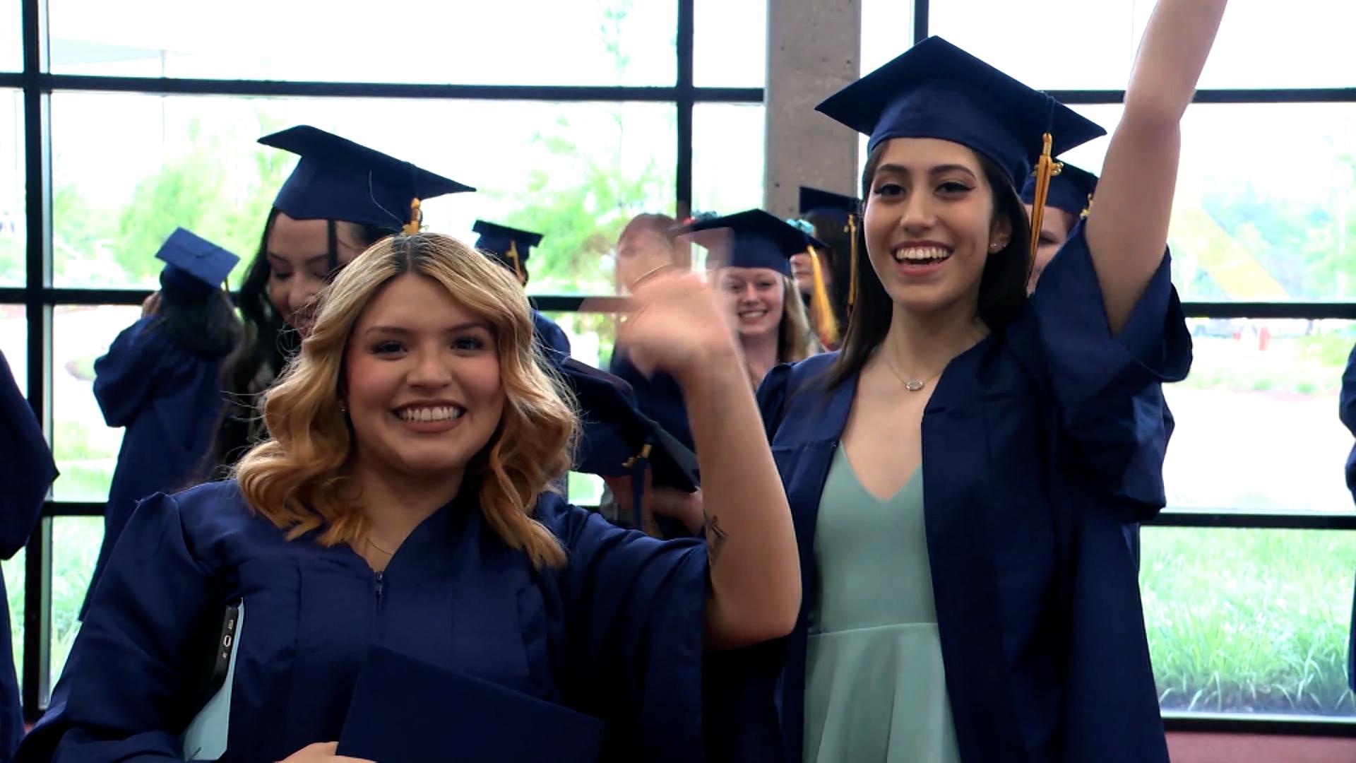 毕业生们戴着帽子，穿着长袍，微笑着挥手